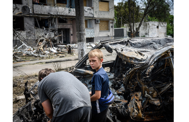 Des enfants cherchent des câbles en cuivre dans le moteur d’une voiture carbonisée, au pied d’un immeuble résidentiel à Pavlohrad, après une frappe russe au moyen d’une bombe guidée le 20 juillet, qui a tué au moins deux civils et en a blessé treize autres (photo Guillaume Herbaut/Prix de Photographie Marc Ladreit de Lacharière/Académie des beaux-arts).