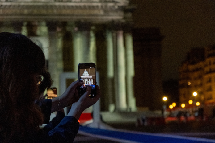 Smartphone en train de prendre une photo du Panthéon lors de la cérémonie nationale d’hommage à Robert Badinter, le 9 octobre 2025 (photo Lou Dumas/Hans Lucas/AFP).