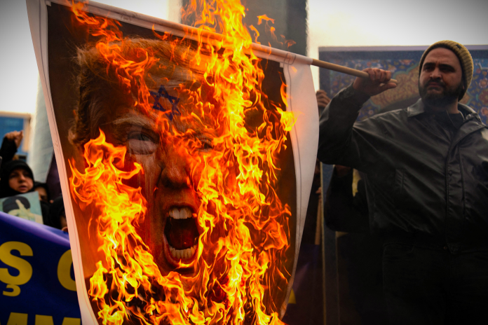 Une photo du président américain Donald Trump incendiée, le 1er mars, lors d'une manifestation devant le consulat israélien à Istanbul, après l'annonce de la mort de l'Ayatollah Khamenei (photo Robert Badendieck/Middle East Images/AFP). 