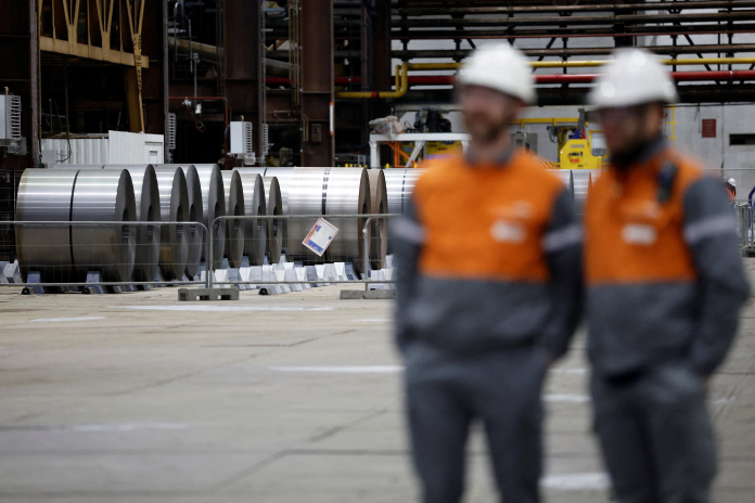 Salariés d'ArcelorMittal devant des bobines d'acier (photo Benoit Tessier/AFP).