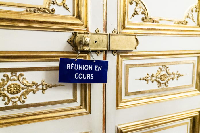 Affichette indiquant qu'une réunion est en cours, à une porte de l'Hôtel de Matignon, en juin 2026 (photo Quentin de Groeve/Hans Lucas/AFP).
