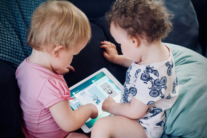 Deux jeunes enfants jouant sur une tablette (photo Jelleke Vanooteghem/Unsplash).