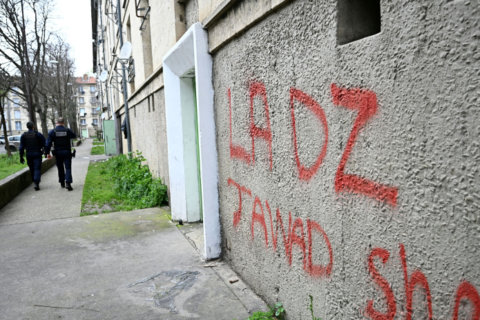 Des policiers patrouillent le long d'un mur tagué au nom de la "DZ" mafia, à Avignon (Photo Gabriel Bouys / AFP)
