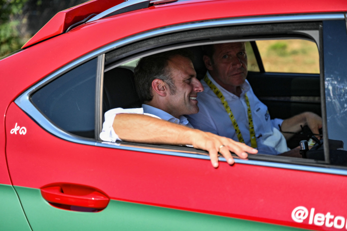 Emmanuel Macron, dans la voiture de Christian Prudhomme, directeur de la course, lors d'une étape du Tour de France, le 17 juillet 2025 (photo Marco Bertorello/AFP).